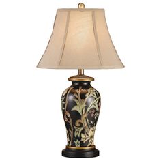 a lamp with a black and gold vase on the base is lit by a white shade