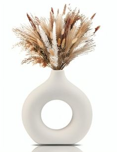 a white vase with some dried plants in it