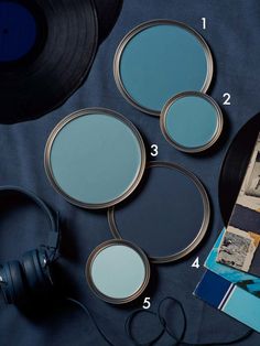 four different shades of blue on a table with headphones and record player next to it