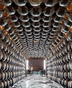 two people standing in the middle of a room filled with metal objects