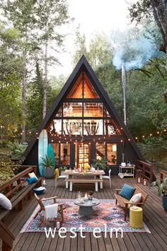 a house in the woods with lots of furniture and decor on it's deck