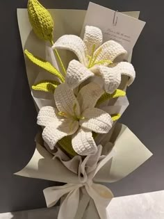 a bouquet of flowers is wrapped in white paper and tied with a light green ribbon