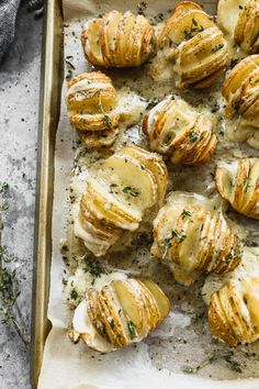 baked potatoes covered in cheese and herbs on a baking sheet, ready to be eaten