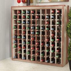 a wooden wine rack with many bottles in it and a potted plant next to it