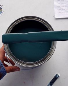 a person is holding a paintbrush in their hand and painting the inside of a can