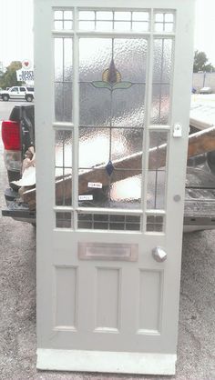 a white door with glass on the side of it in front of a pickup truck