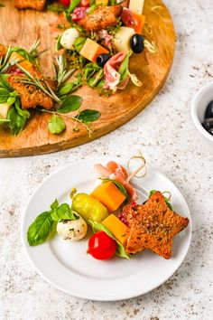 a white plate topped with salad next to a wooden platter filled with meat and veggies