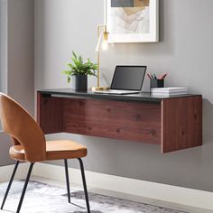 a desk with a laptop on it next to a chair and potted plant in the corner