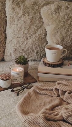 a cozy bed with candles, books and a cup of coffee