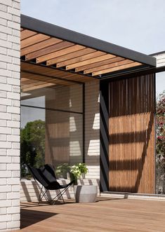 a black chair sitting on top of a wooden floor next to a white brick building