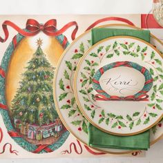 a christmas themed place setting with a tree on the plate and red ribbon around it