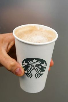 a hand holding a starbucks cup with foam