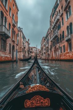 a boat traveling down a river next to tall buildings on either side of the water