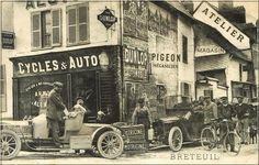 an old time photo of men in front of bicycles and auto