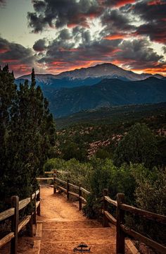 a bike is parked on a dirt path with mountains in the background at sunset or dawn