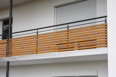 a wooden balcony railing on the side of a white building with an open garage door