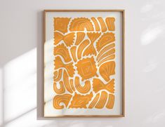 an orange and white art piece hanging on a wall next to a window with sunlight coming in