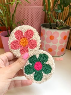 two crocheted flower coasters sitting on top of a table next to a potted plant