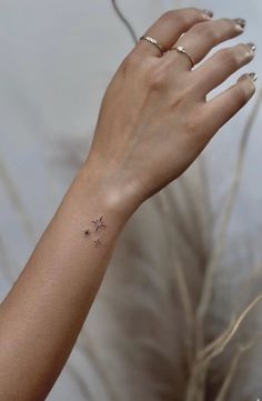 a woman's hand with a tiny star tattoo on her left wrist, next to some dry grass