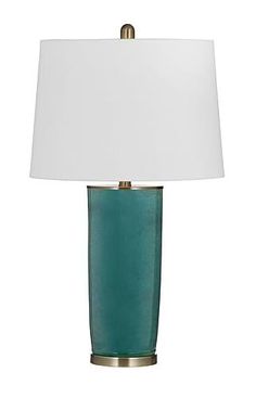 a green lamp with a white shade on it's side and a gold base