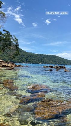 the water is crystal clear and there are rocks on the shore in the foreground