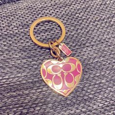 a pink and gold heart shaped keychain sitting on top of a gray blanket