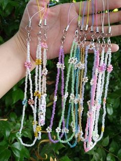 a hand holding several different colored necklaces in it's left hand, with other beads hanging from them