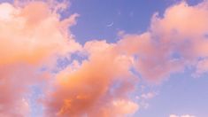 an airplane flying in the sky with clouds and a half moon behind it at sunset