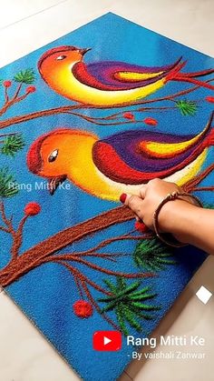 a person is painting on the floor with colorful birds