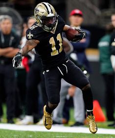 a football player running with the ball in his hand and people watching from the sidelines