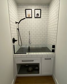 a white tiled bathroom with black and white tile on the walls, an overhead shower head is in the corner