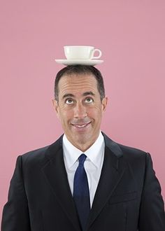 a man in a suit and tie with a coffee cup on top of his head