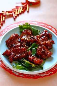 a white plate topped with meat and greens on top of a red and white table