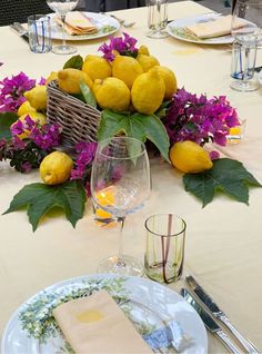 the table is set with lemons and purple flowers