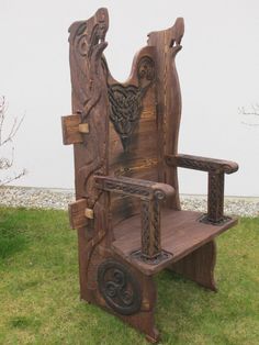 a chair made out of wood sitting on top of a green grass covered field next to a white wall