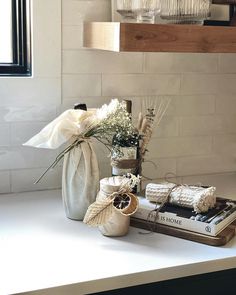 some flowers are in a vase on a counter top next to books and other items