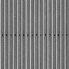 some black dots are on the side of a metal wall and there is no image to describe