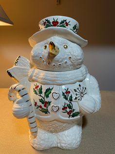 a white ceramic snowman holding a candy cane