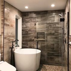 a bathroom with a tub, toilet and shower in it's center wall that has wood paneling on the walls