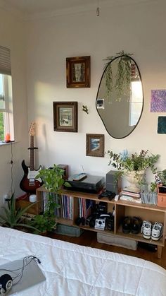 a bedroom with a bed, bookshelf and various plants