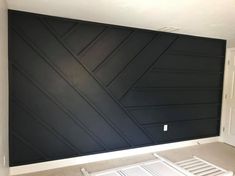 an empty room with black painted walls and white shutters on the wall, in front of a flat screen tv