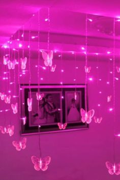 pink lights hang from the ceiling in a room with butterflies hanging from it's walls