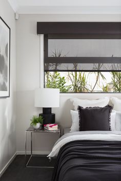 a bedroom with black and white bedding, two nightstands and a painting on the wall