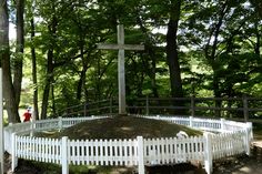 a cross on top of a white fence in the woods