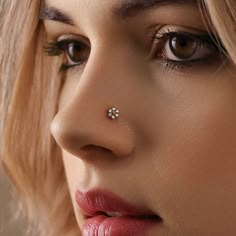 a close up of a woman with a nose ring on her nose and piercing in the middle