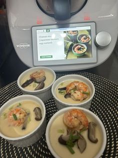 four bowls of soup with shrimp and clams in front of an appliance