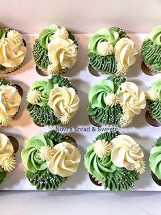 twelve cupcakes with green and white frosting arranged in a box on a table