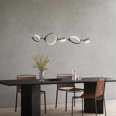 a dining room table with chairs and lights hanging from the ceiling