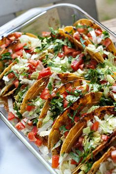 a tray filled with tacos sitting on top of a table