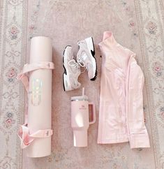 the contents of a woman's pink outfit laid out next to a travel mug